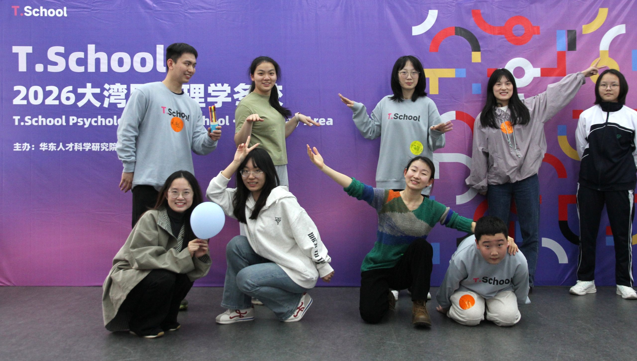 T.School大湾区心理学冬校师生在紫色活动背景板前合影